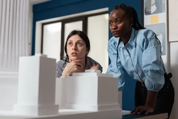 project engineers women colleagues looking inspired front 3d residential maquette architectural modern office focused professional architects team inspecting skyscraper white foam model